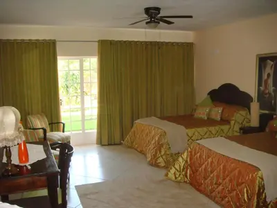 a bedroom with two beds and a window with green curtains at Heatherdale Guesthouse & Shuttle Services in Pretoria
