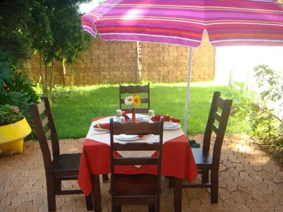 a table under an umbrella with a table and chairs at Heatherdale Guesthouse & Shuttle Services in Pretoria
