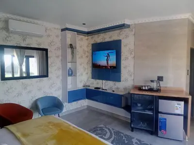 a room with a bed and a desk with a tv on the wall at Lesiba guesthouse in Kwamhlanga