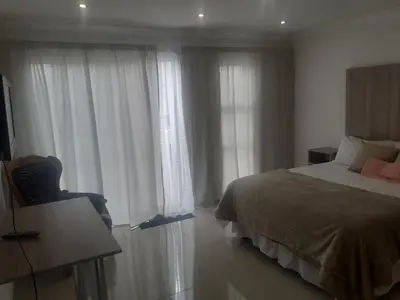 a bedroom with a bed and a window with white curtains at Lesiba guesthouse in Kwamhlanga