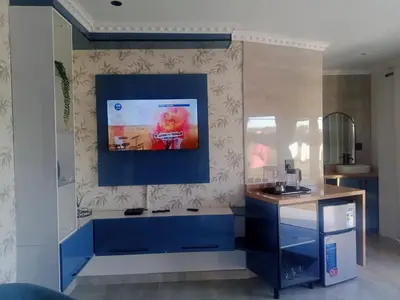 a kitchen with blue cabinets and a tv on the wall at Lesiba guesthouse in Kwamhlanga