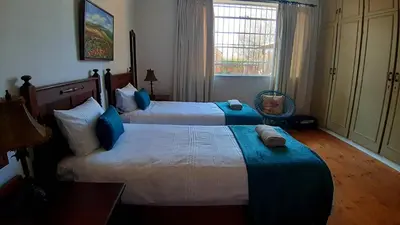 a hotel room with two beds and a window at Bluebell Country House in Dullstroom