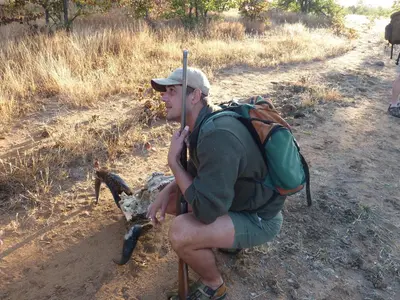 a man with a backpack sitting next to a sheep at Bush Villas on Kruger in Phalaborwa