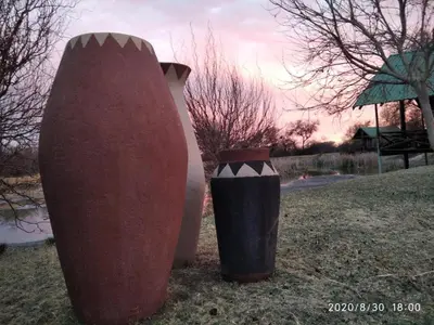 two large vases and a trash can in a field at Hanlin Lodge in Modimolle