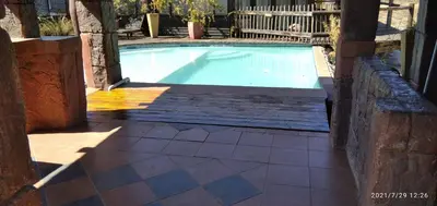 a swimming pool in a yard with a wooden deck at Hanlin Lodge in Modimolle