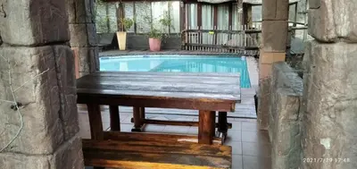 a wooden bench sitting next to a swimming pool at Hanlin Lodge in Modimolle