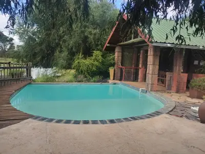 a large swimming pool in front of a house at Hanlin Lodge in Modimolle