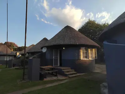 a small blue building with a grass roof at Graskop family retreat and backpackers in Graskop