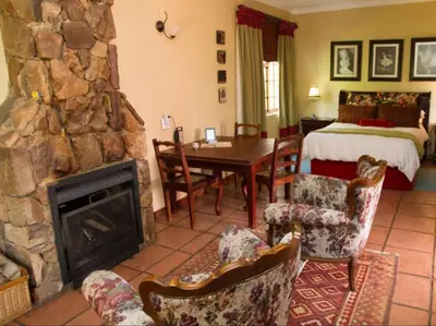 a living room with a stone fireplace and a bedroom at Jocks Cottages in Dullstroom