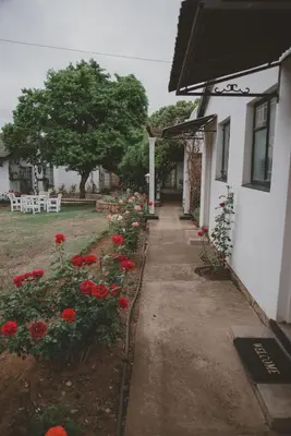 a sidewalk next to a house with red flowers at Lydenburg Manor Guest House in Lydenburg