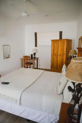 a bedroom with a white bed with a lamp and a table at Lydenburg Manor Guest House in Lydenburg