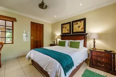 a bedroom with a large bed with green pillows at Country Lane Lodge in White River