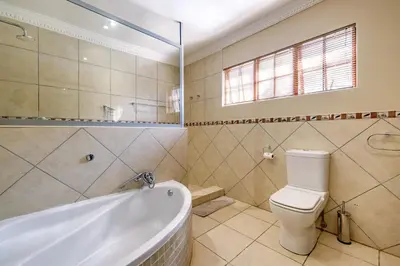 a bathroom with a tub and a toilet and a sink at Country Lane Lodge in White River