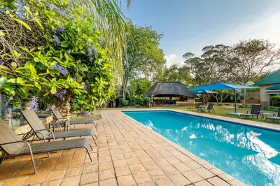 a swimming pool with lounge chairs next to a house at Country Lane Lodge in White River