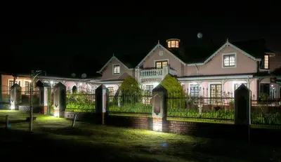 a large white house with a fence at night at Westlodge at Graskop B&B in Graskop