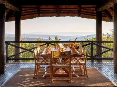 a table on a deck with a view of the ocean at Tintswalo Waterberg in Vaalwater