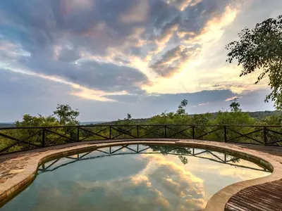 a bridge over a pool with a cloudy sky at Tintswalo Waterberg in Vaalwater