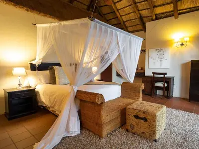 a bedroom with a canopy bed and a chair at Tintswalo Waterberg in Vaalwater