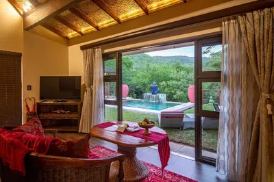 a living room with a table and a large window at The Zarafa in Hazyview