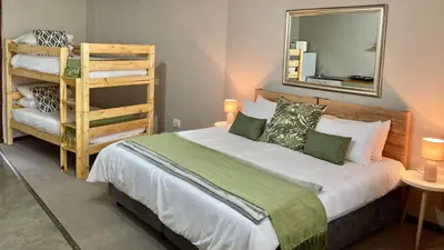 a bedroom with a bed with a mirror and a ladder at Aloe Cottage in Nelspruit