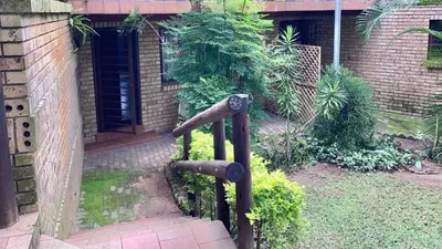 a metal gate leading to a brick building with a staircase at Aloe Cottage in Nelspruit