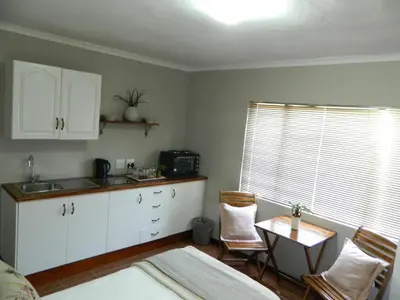 a kitchen with white cabinets and a table with chairs at Aloe Cottage in Nelspruit