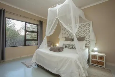 a bedroom with a white bed with a canopy at Klein Paradys in Marloth Park