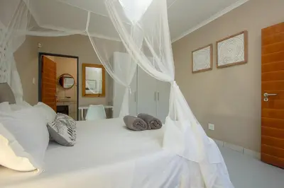 a bedroom with a white bed with a canopy at Klein Paradys in Marloth Park