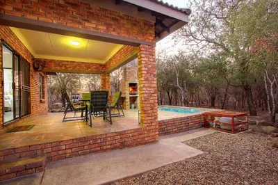 a brick patio with a table and chairs and a pool at Klein Paradys in Marloth Park