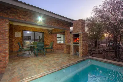 a patio with a table and chairs and a fireplace at Klein Paradys in Marloth Park
