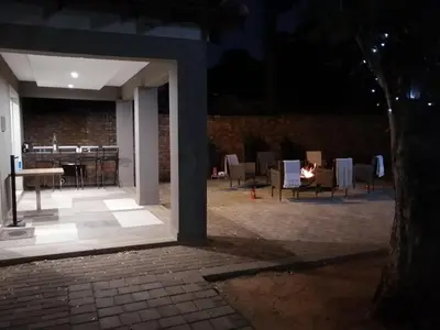 an outdoor patio at night with chairs and a fire at Shai's Nest in Centurion