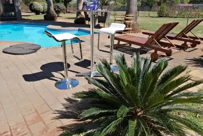 a patio with chairs and a table next to a pool at Shai's Nest in Centurion