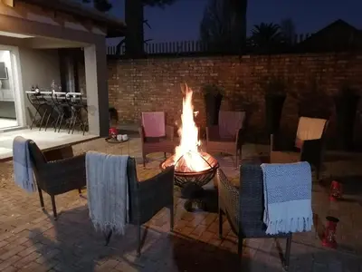 a fire pit in a patio with chairs and a table at Shai's Nest in Centurion