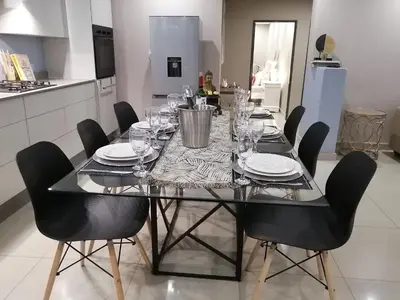 a dining table with chairs and plates and wine glasses at Shai's Nest in Centurion
