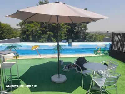 a table and chairs under an umbrella in the grass at JB Countrylife Accommodation in Koedoe