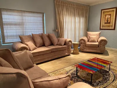 a living room with a brown couch and two chairs at JB Countrylife Accommodation in Koedoe