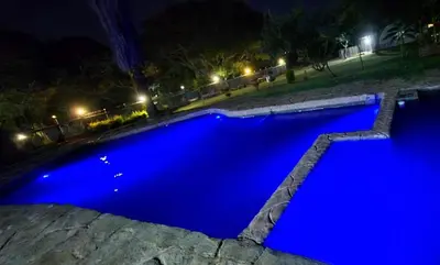 a blue swimming pool at night with at Hide Away Wedding,Conference & Function Venue in Bela-Bela