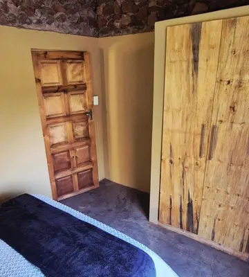 a bedroom with a bed and a large wooden door at Hide Away Wedding,Conference & Function Venue in Bela-Bela