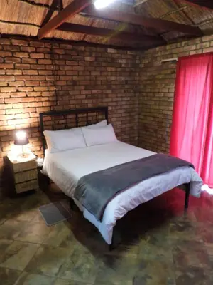 a bedroom with a large bed with a red curtain at Hide Away Wedding,Conference & Function Venue in Bela-Bela