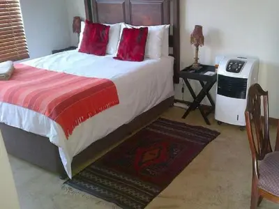 a bedroom with a large bed with red pillows at Monacco Guest house in Erasmus