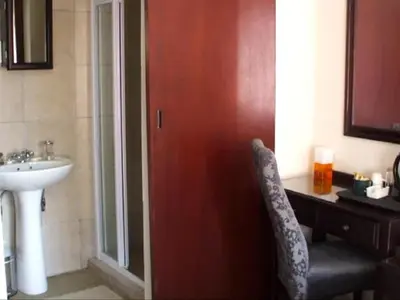 a bathroom with a sink and a red door with a chair at Monacco Guest house in Erasmus