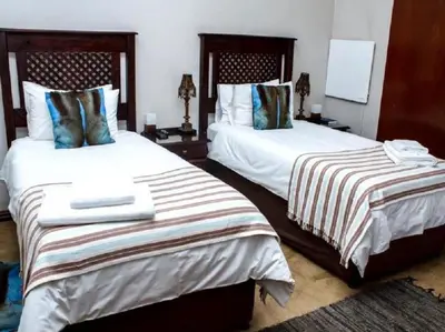 two beds in a hotel room withskirts at Monacco Guest house in Erasmus