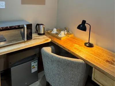 a wooden table with a microwave and a lamp on it at Thabazimbi Country Lodge in Thabazimbi