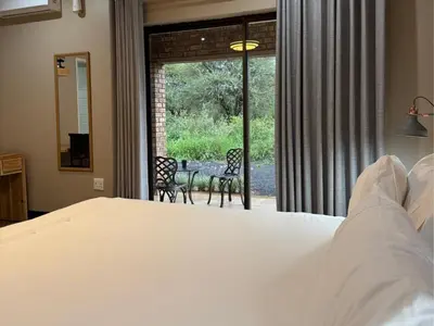 a bedroom with a bed and a table and chairs at Thabazimbi Country Lodge in Thabazimbi