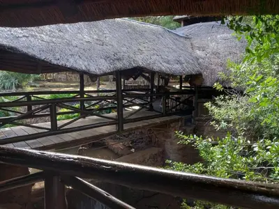 a hut with a thatched roof and a wooden deck at Glen Afric Country Lodge in Hartbeespoort