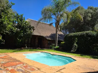 a swimming pool in front of a house at Glen Afric Country Lodge in Hartbeespoort