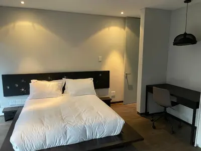 a bedroom with a large white bed and a desk at Ten On Lane in Polokwane