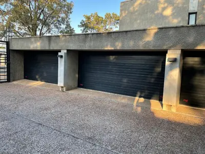 two garage doors on a building with trees in the background at Ten On Lane in Polokwane