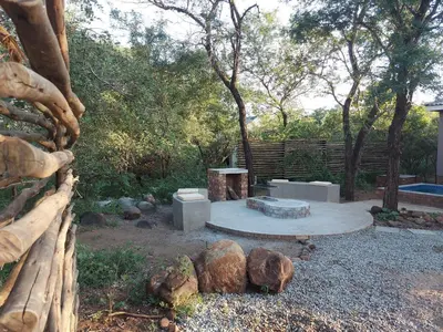 a fire pit in a yard with trees and rocks at 3714 @Ribbok in Marloth Park