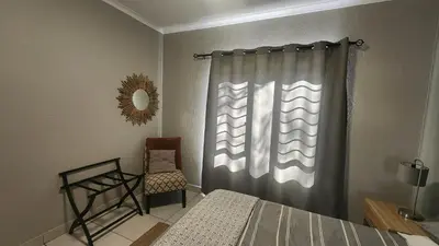 a bedroom with a bed and a window with a chair at 3714 @Ribbok in Marloth Park